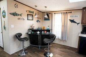 A kitchen with a bar area, wooden cabinets, and a sign reading 'BEACH HOUSE'. - Stay Under the Stars in Chincoteague (Chincoteague)