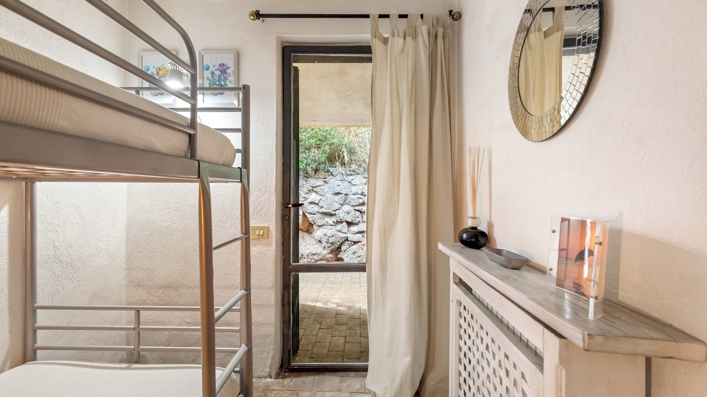 Habitación con literas, pared de piedra en el exterior, un espejo y una mesita con una vela.