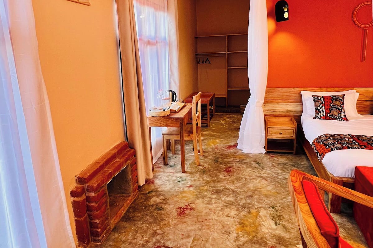A room with a bed, a chair, a table, and a window.