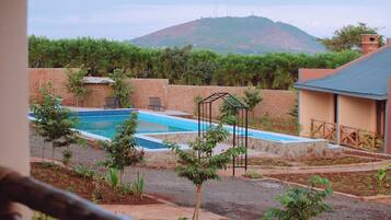 A swimming pool with a view of a mountain, surrounded by a brick wall and greenery.