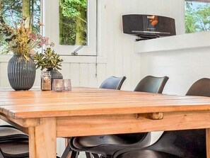 A dining table with chairs, a vase with flowers, and a television mounted on the wall. - 5 Star Holiday Home in Bindslev (Bindslev)