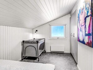 A bedroom with a bunk bed, a pet bed, a window, and a painting on the wall. - 5 Star Holiday Home in Bindslev (Bindslev)