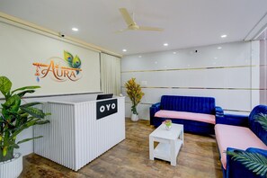 A reception area with a reception desk labeled 'OYO,' a blue sofa, a white coffee table, and a ceiling fan. - Townhouse Sunnam Cheruvu Lake (Hyderabad)