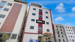 Un immeuble hôtelier à plusieurs étages, avec une enseigne bien visible indiquant « Hôtel Aura » et « OYO ».