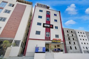 A multi-story hotel building with a prominent sign for 'Hotel Aura' and 'OYO.' - Townhouse Sunnam Cheruvu Lake (Hyderabad)
