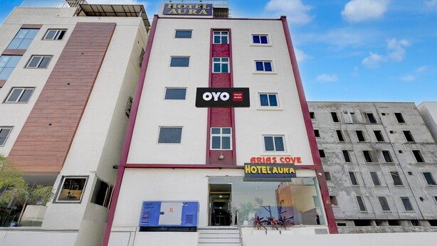 Un hôtel à plusieurs étages, avec des enseignes indiquant « Hôtel Aura » et « Hôtel OYO Aurora ».