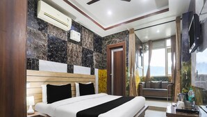 Een moderne hotelkamer met een groot bed, een houten hoofdeinde, een televisie en uitzicht op het groen.
