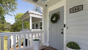 Uma casa branca com varanda, uma porta adornada com uma guirlanda e uma caixa de correio.