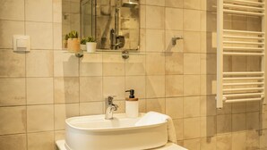 A bathroom with a sink, mirror, towel rack, and patterned floor tiles.