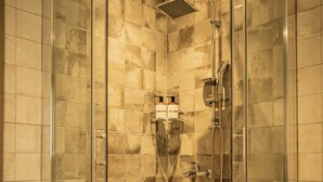 A glass-enclosed shower with a showerhead and handheld shower, tiled walls, and patterned floor tiles.