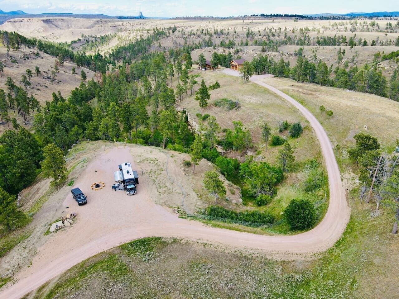 An aerial view of a campsite with a dirt road, a tent, and a vehicle.