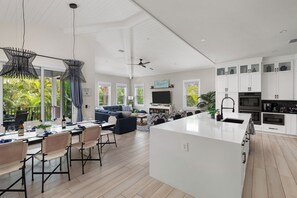 Una cocina moderna con armarios blancos, una isla central y un comedor con mesa y sillas.