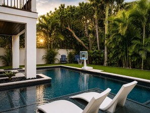 A swimming pool with lounge chairs, a basketball hoop, and lush greenery. - Heart of Pine Ave | 6 En-Suites | Heated Pool (Anna Maria)