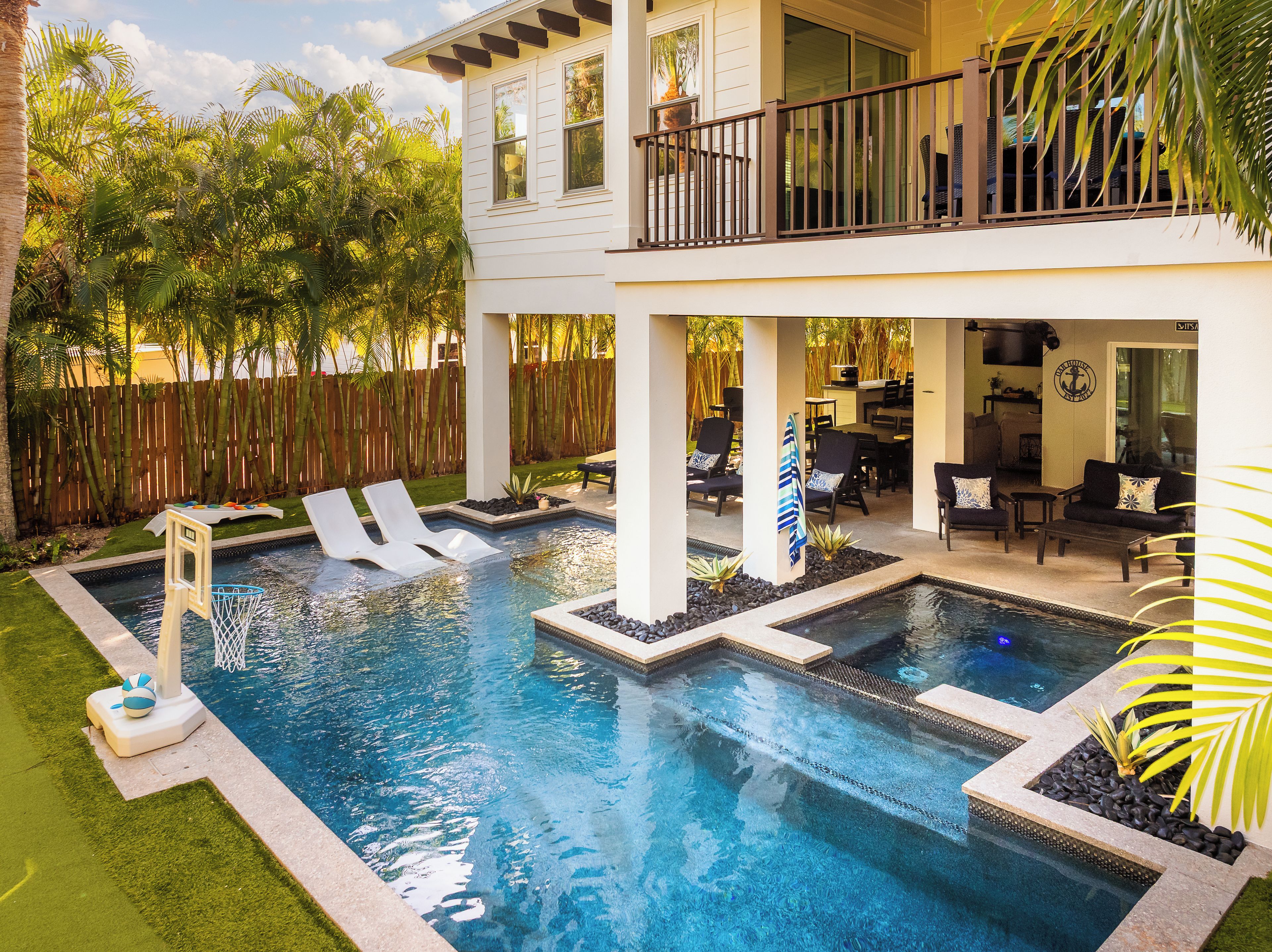 A two-story house with a swimming pool, outdoor furniture, and a wooden fence.