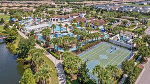 An aerial view of a residential area with multiple houses, a swimming pool, and a tennis court. - Upstay Lake View Villa with Hot Tub, Pool & Resort (Kissimmee)