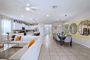A modern kitchen with white cabinets, a microwave, and a dining area with a table and chairs. - Upstay Lake View Villa with Hot Tub, Pool & Resort (Kissimmee)