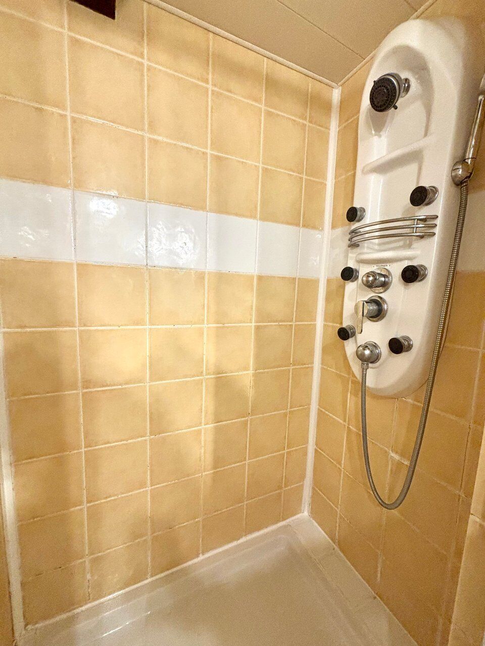A bathroom with beige tiled walls, a white shower enclosure, and a bathtub.