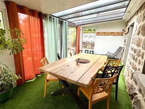 Een eetgedeelte met een houten tafel, stoelen en een glazen plafond.