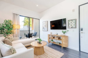 Ein modernes Wohnzimmer mit einer Couch, einem Couchtisch und einem Fernseher an der Wand.