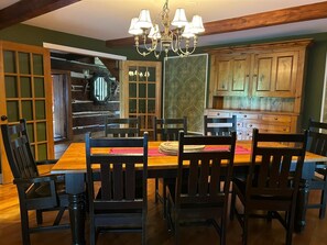 A dining area with a wooden table and chairs, a chandelier, and wooden cabinets.