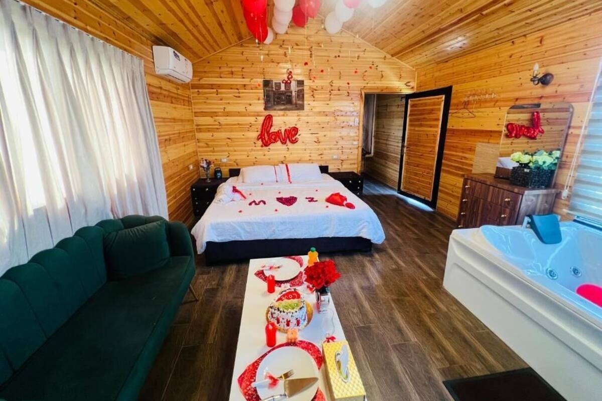 Una habitación acogedora con una cama, un sofá verde, una mesa de comedor y un pastel, además de un jacuzzi.