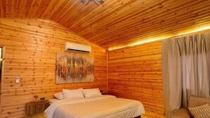 Quarto com painéis de madeira, uma cama, um sofá, uma mesa de centro e um candelabro.