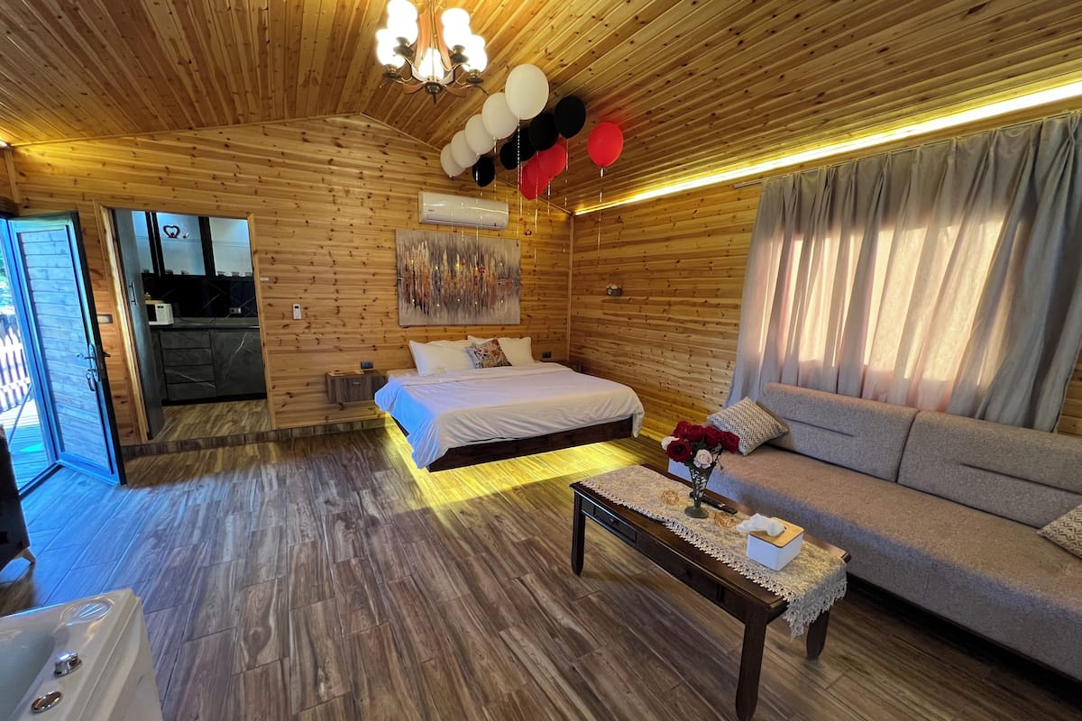 Un interior de madera con una cama, un sofá y una mesa con un florero.