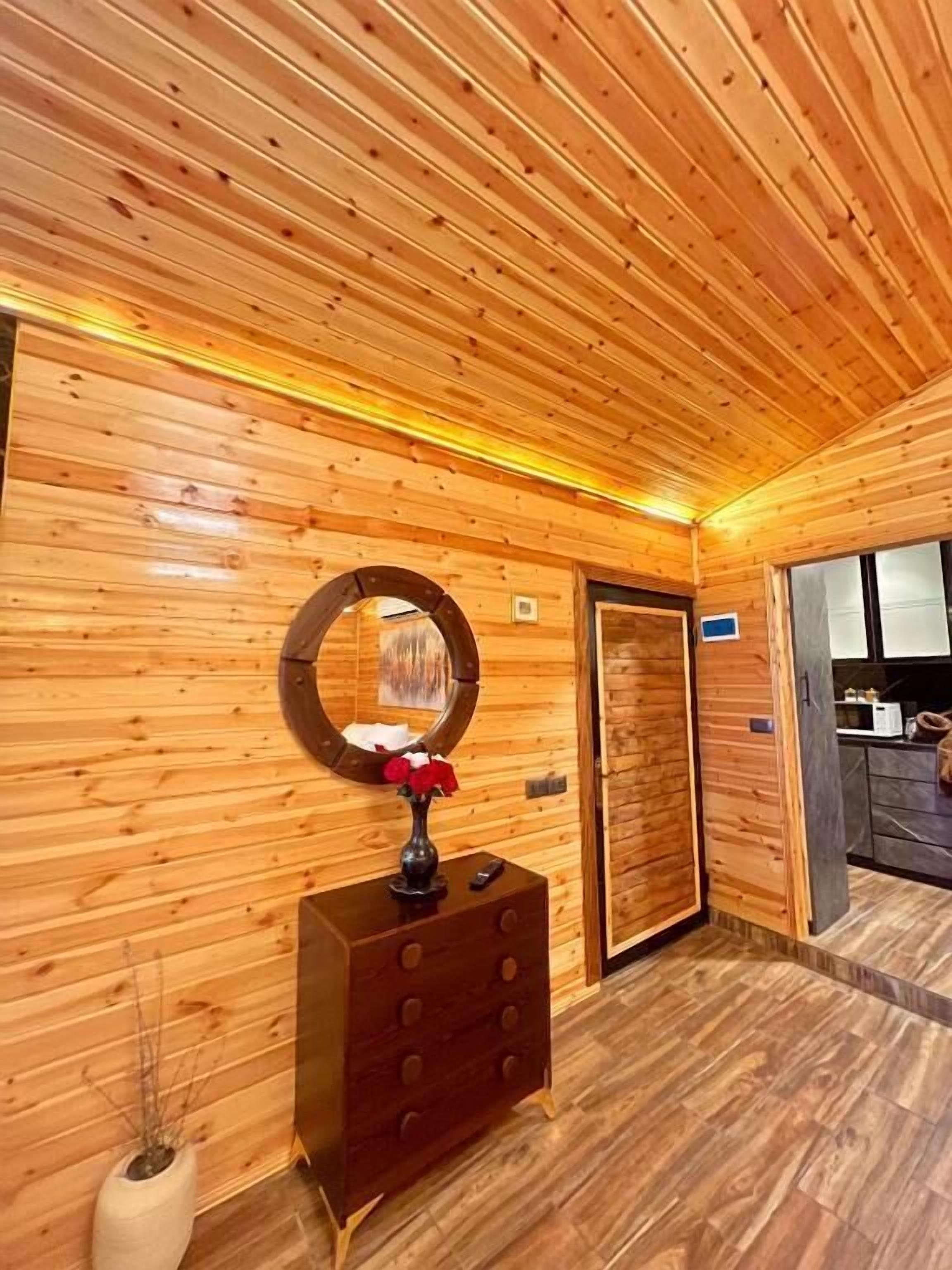 Un interior de madera con pared de madera, un espejo, un aparador y una puerta.