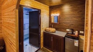 Una cabaña de madera acogedora con una pequeña kitchenette, una puerta que da a un balcón y un espejo en la pared.