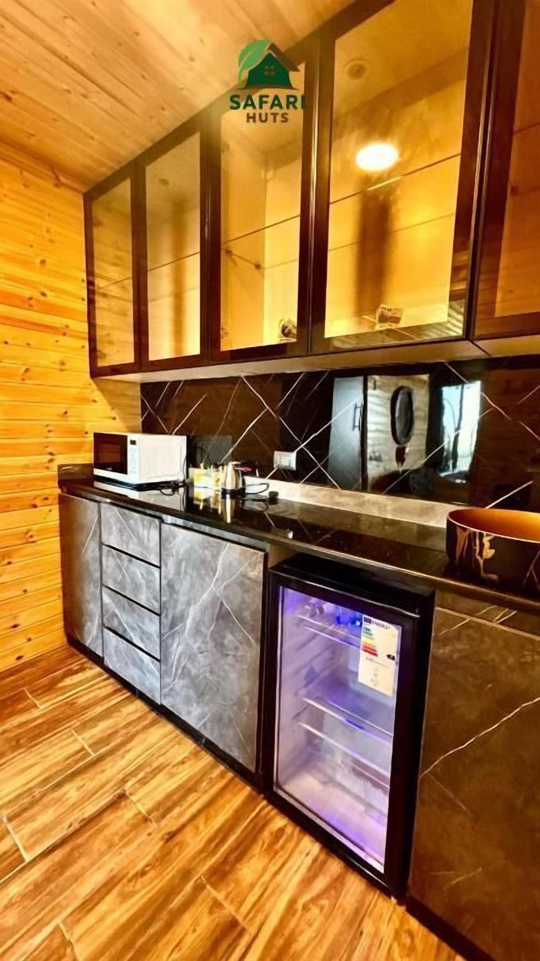 Una cocina compacta con refrigerador, microondas y un lavamanos pequeño.