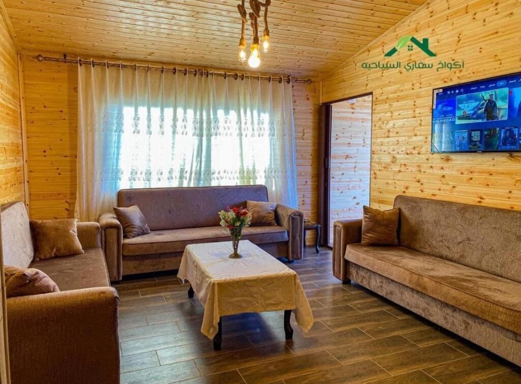 A wooden interior with a sofa, a table with a vase, and a TV on the wall.