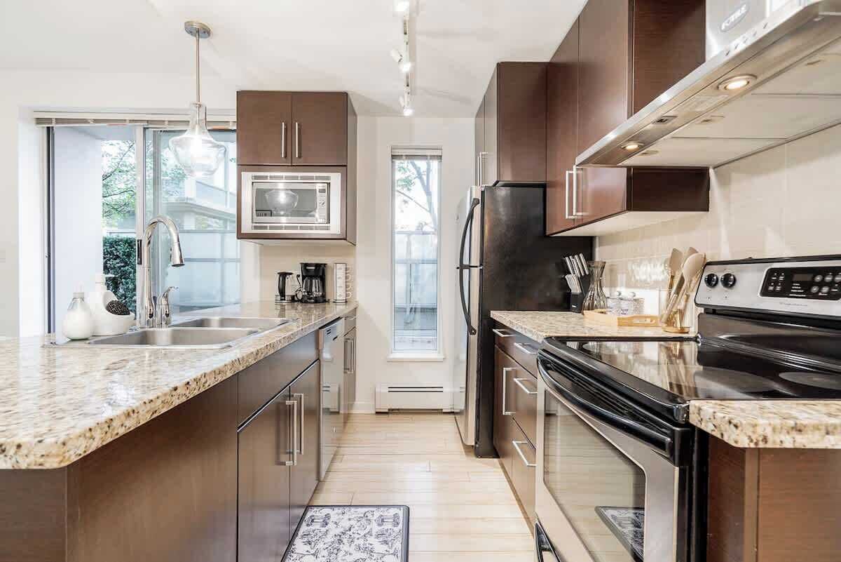 A modern kitchen with granite countertops, stainless steel appliances, and wooden cabinets.