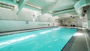 Piscina interna com água cristalina, placa indicando que mergulhos não são permitidos e teto iluminado pelo sol.