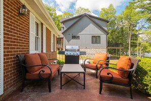 A patio with outdoor furniture, a grill, and a brick building. - Lakefront w Private Dock, Hot Tub, Large Yard (Swanton)
