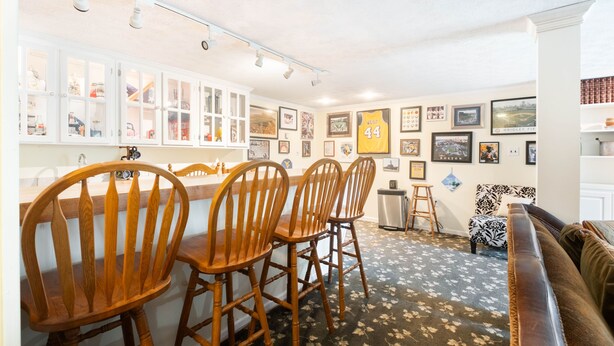 A kitchen with wooden chairs, a bar counter, and a patterned carpet.