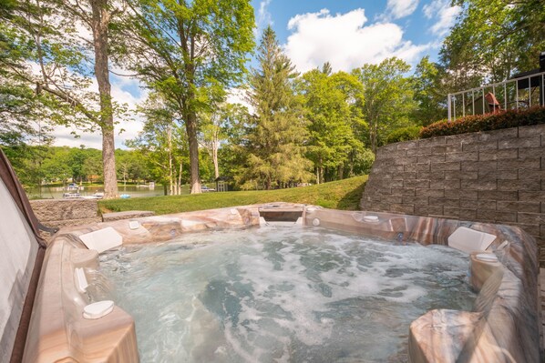 Un jacuzzi rodeado de árboles y un muro de piedra.