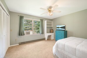 A bedroom with a bed, a desk, a television, and a window with curtains. - Lakefront w Private Dock, Hot Tub, Large Yard (Swanton)