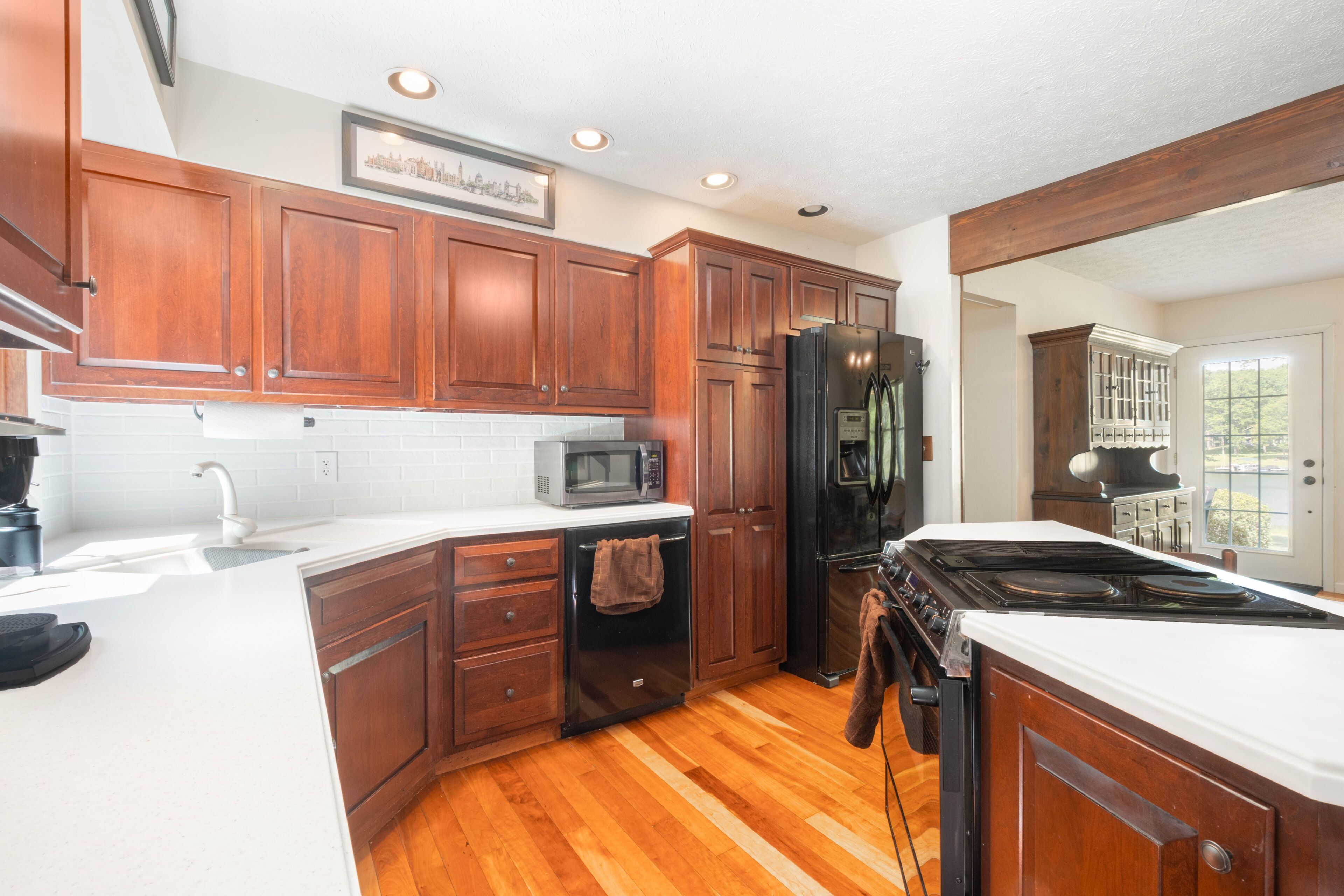 A kitchen with wooden cabinets, a microwave, a refrigerator, and a stove.