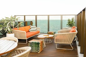 Un balcón con mobiliario de mimbre, un sofá y vista al mar.