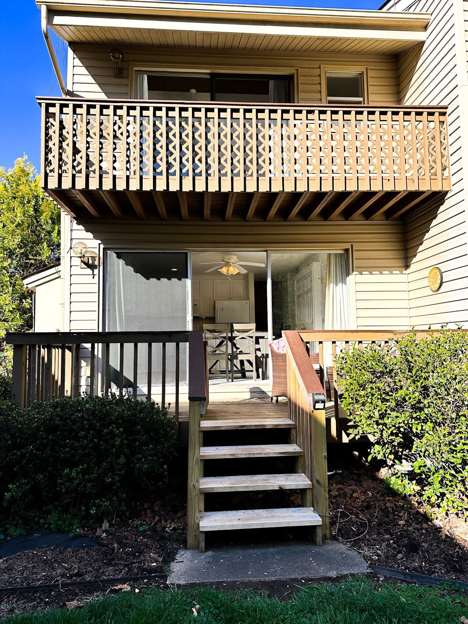 A two-story house with a wooden balcony, a front door, and a staircase leading to the entrance.