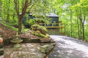 Ein Haus mit Veranda, umgeben von Bäumen und einem Kiesweg.