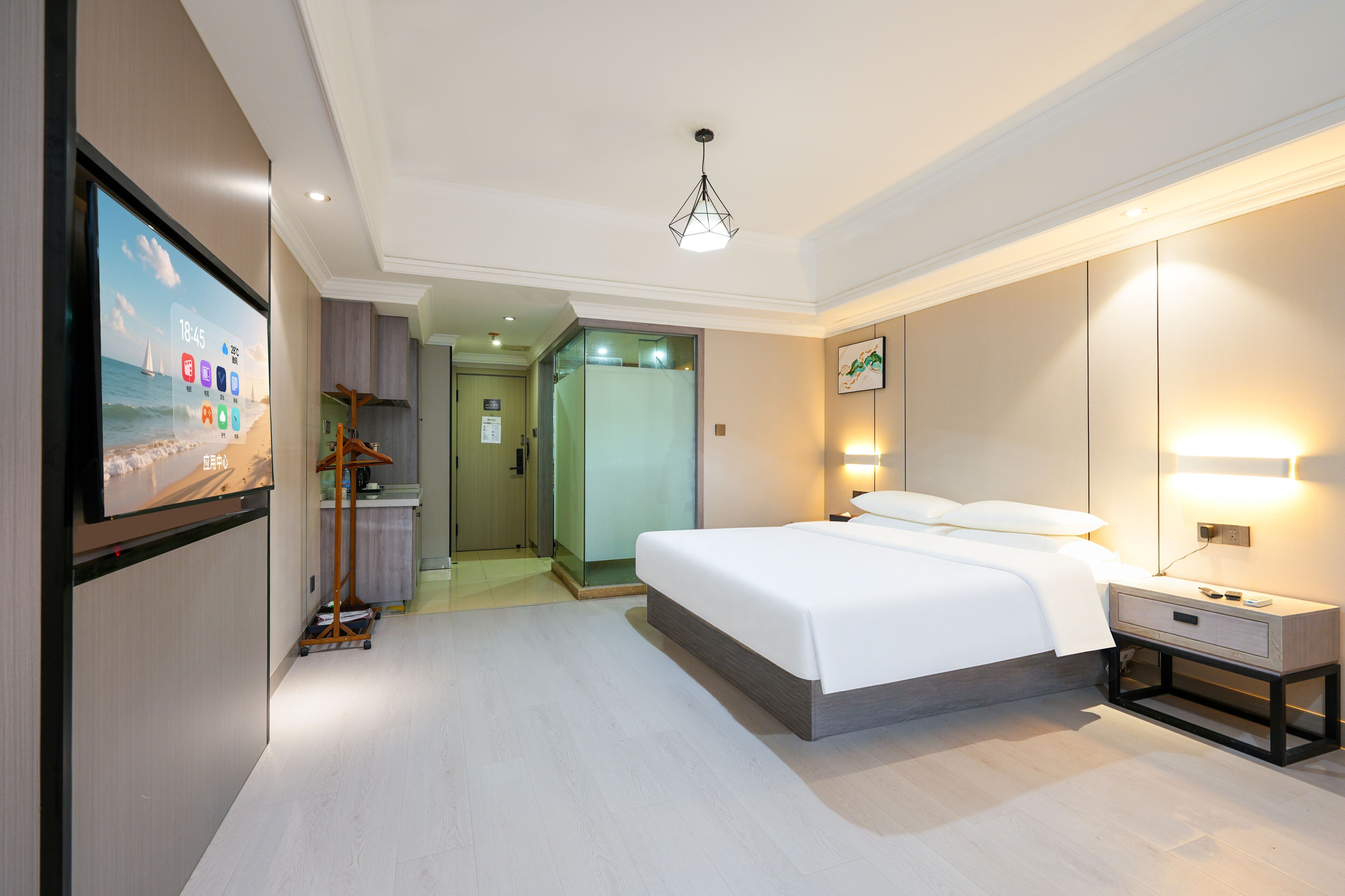 A modern hotel room with a large bed, bedside table, and a flat-screen TV mounted on the wall.