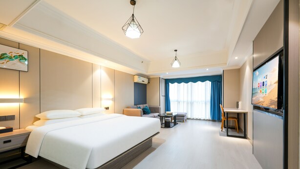 Ein modernes Hotelzimmer mit einem großen Bett, Nachttischen, einem Schreibtisch und einem Fernseher.