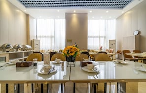 Ein Hotelrestaurant mit mehreren Tischen, Stühlen und einer zentralen Blumenkomposition.