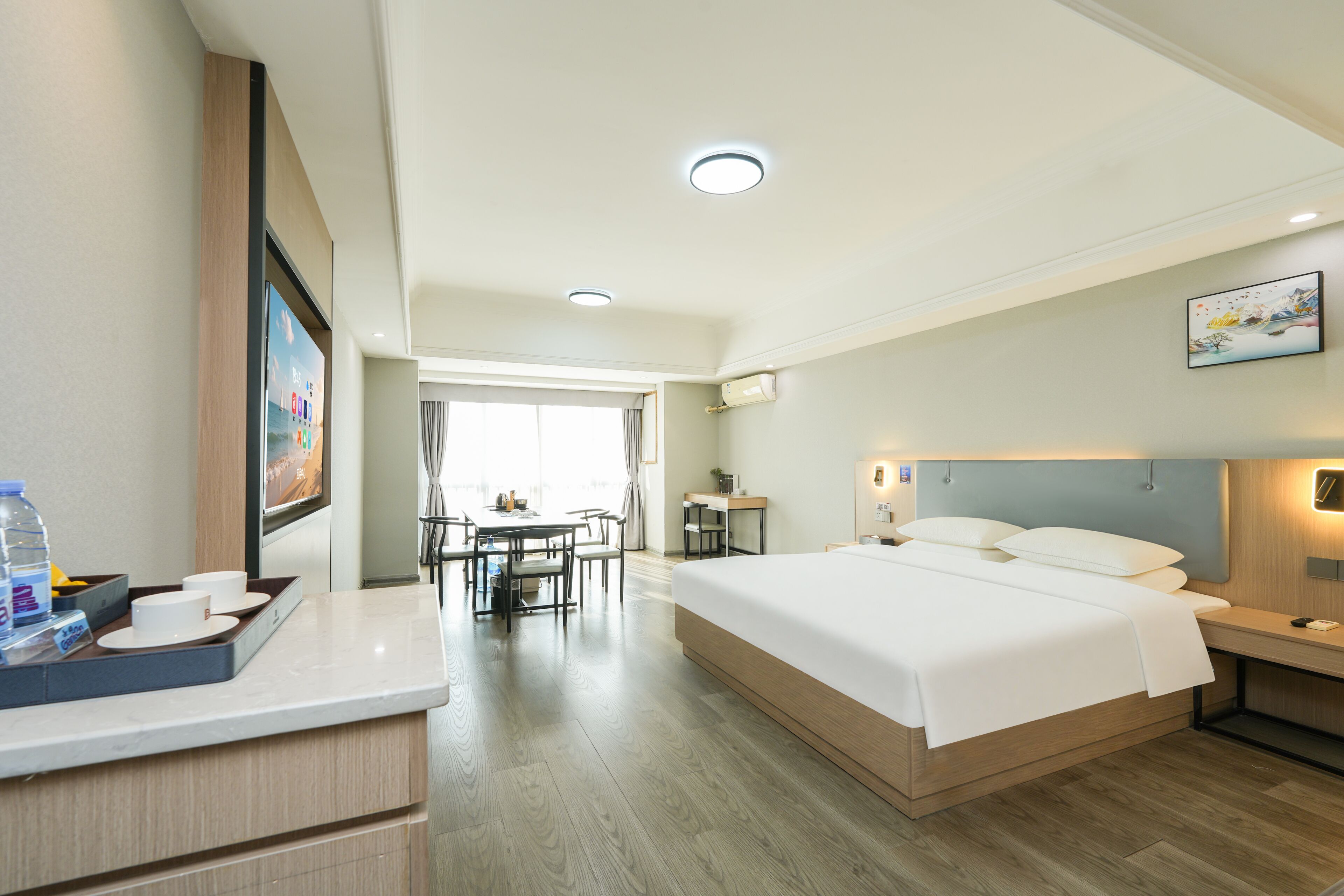 Una habitación de hotel con una cama grande, un escritorio, una silla, una mesa de comedor y un televisor.