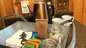 Ein Tablett mit einer Kaffeemaschine, einem Wasserkocher, einer Zuckerdose und Teebeuteln auf einer Küchenarbeitsfläche.