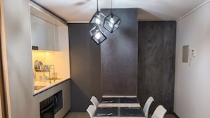 A modern kitchen with a built-in dishwasher, a dining table with chairs, and a pendant light fixture. - Centro Cívico - La Moneda - Domus Travels (Santiago)