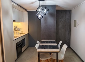 Una cocina moderna con lavavajillas incorporado, una mesa de comedor con sillas y una lámpara colgante.