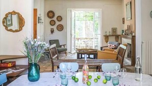 A dining area with a table set for four, chairs, a vase with flowers, and a view of the garden through the open door. - Notre Dame des Miracles - In the Heart of Avignon - Private Pool - 14 people (Avignon)