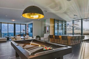 A modern pool table with a bar area, seating, and a view of the cityscape. - Presidential Penthouse Private Infinity Pool (Miami)